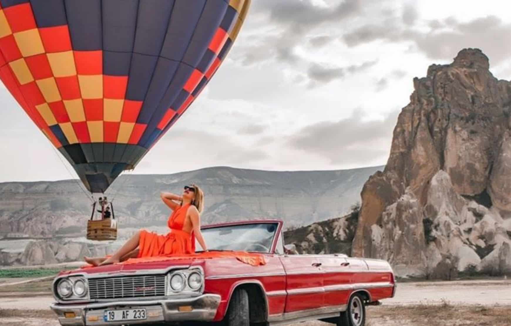 a red dressed woman sitting on a vintage car at our Cappadocia Classic Car Tour