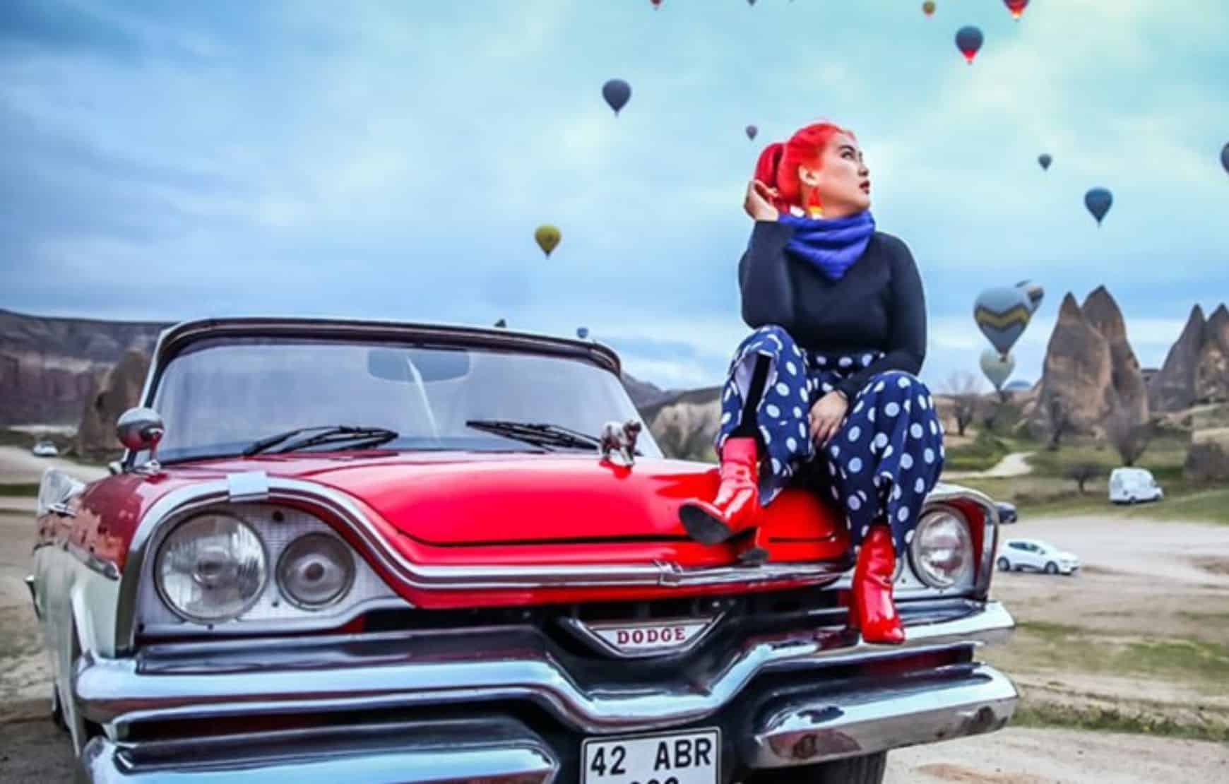 a red hair woman sitting on a vintage car at our Cappadocia Classic Car Tour